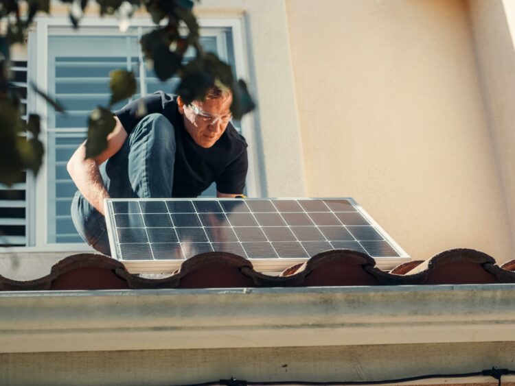 Person montiert Solaranlage am Dach.